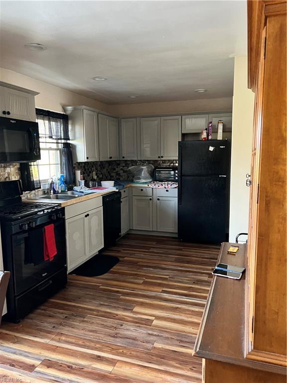 kitchen with black appliances, light hardwood / wood-style floors, sink, and backsplash