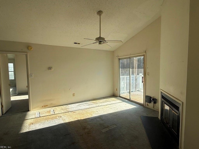 unfurnished living room with ceiling fan, a healthy amount of sunlight, a textured ceiling, and vaulted ceiling