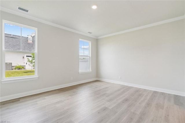 unfurnished room with a wealth of natural light, light hardwood / wood-style flooring, and ornamental molding