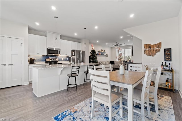 dining room with ceiling fan, sink, and light hardwood / wood-style flooring