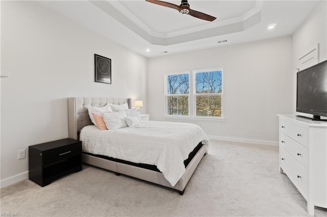 bedroom featuring ceiling fan, a raised ceiling, light colored carpet, and crown molding