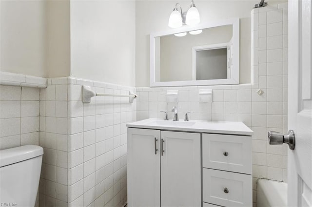 bathroom featuring vanity, tile walls, and toilet