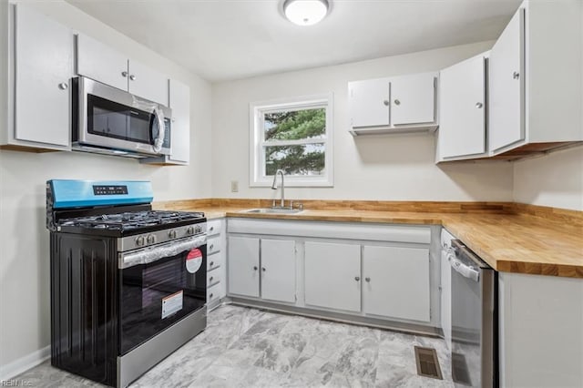 kitchen with white cabinets, sink, butcher block counters, and stainless steel appliances