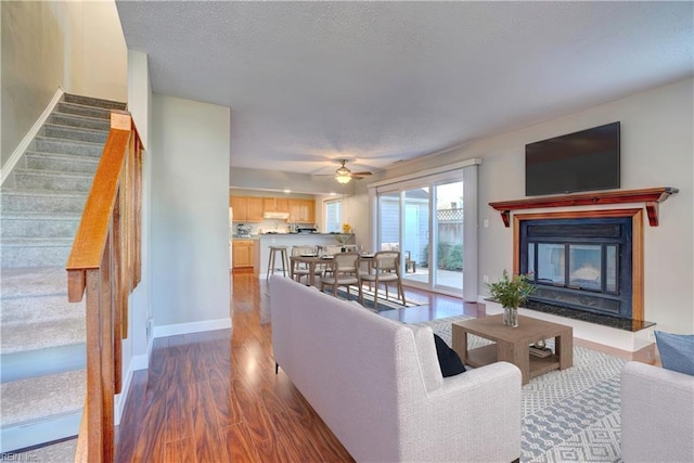 living room with ceiling fan, dark hardwood / wood-style flooring, and a textured ceiling