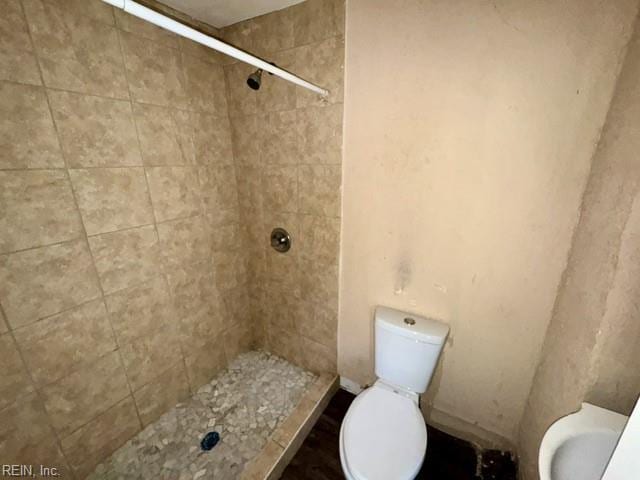 bathroom featuring toilet and tiled shower