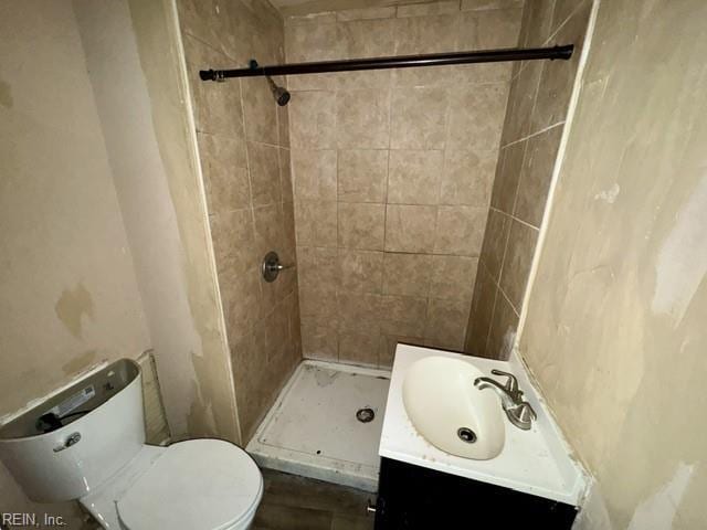 bathroom featuring vanity, toilet, and tiled shower