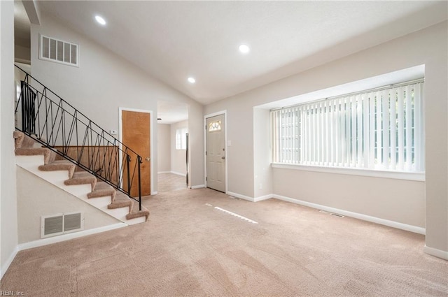 carpeted entrance foyer with a wealth of natural light and high vaulted ceiling