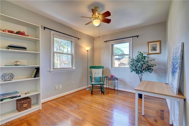 sitting room with built in features, light hardwood / wood-style flooring, ceiling fan, and a healthy amount of sunlight