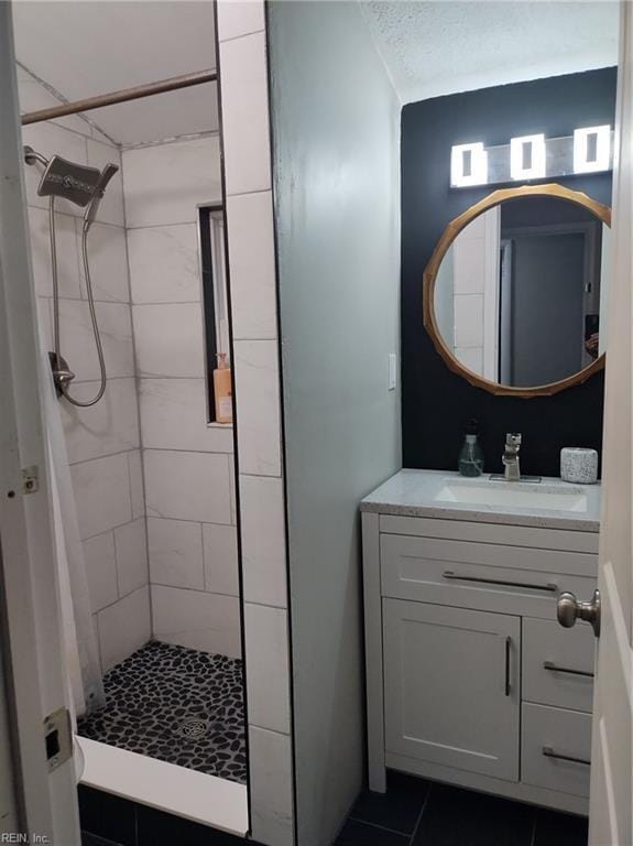 bathroom with tiled shower, vanity, and tile patterned flooring