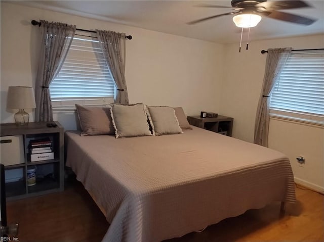 bedroom with multiple windows, wood-type flooring, and ceiling fan