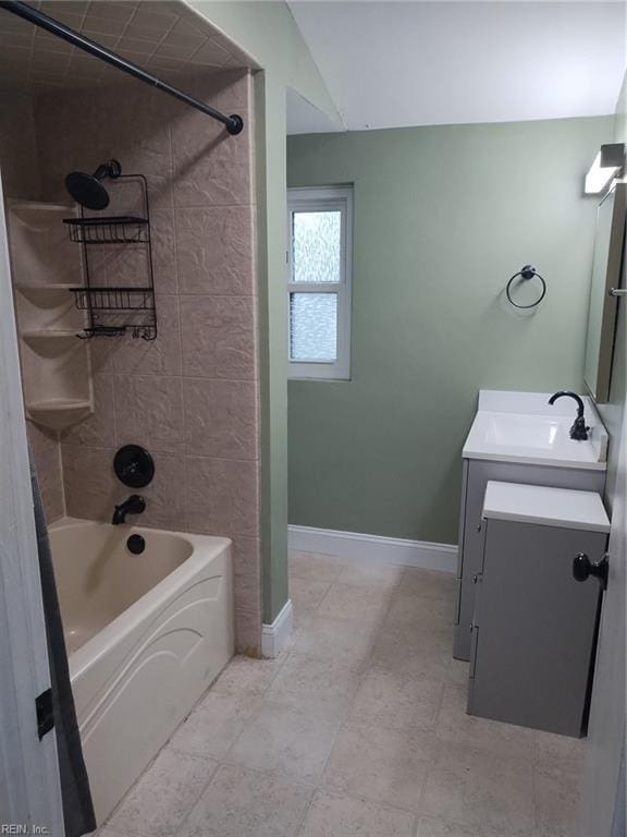 bathroom with vanity, tiled shower / bath, and vaulted ceiling