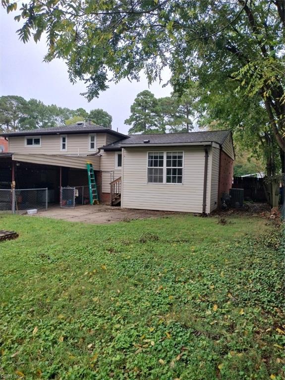 back of property featuring cooling unit and a lawn