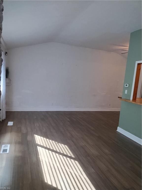 spare room with dark hardwood / wood-style floors, ceiling fan, a fireplace, and vaulted ceiling