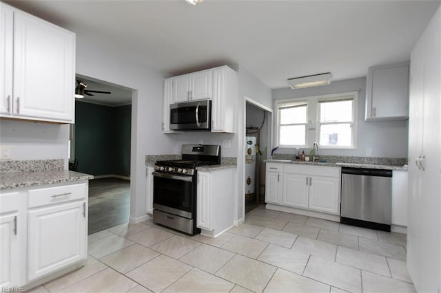 kitchen with ceiling fan, stainless steel appliances, white cabinets, water heater, and light tile patterned floors