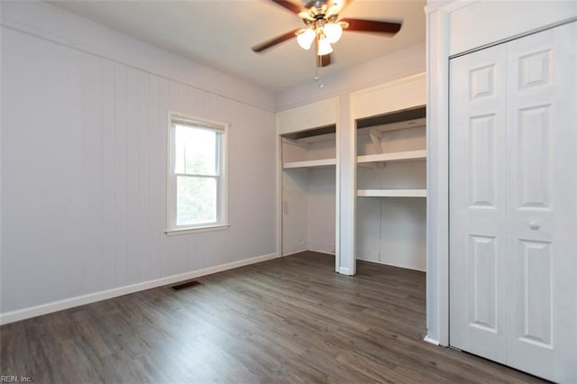 unfurnished bedroom with multiple closets, ceiling fan, and dark wood-type flooring