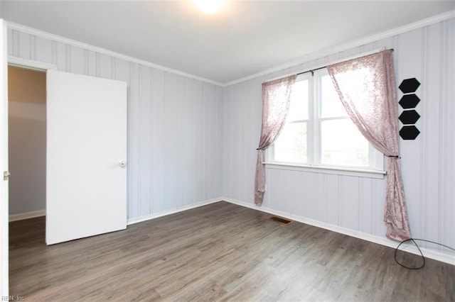 empty room with hardwood / wood-style flooring and crown molding