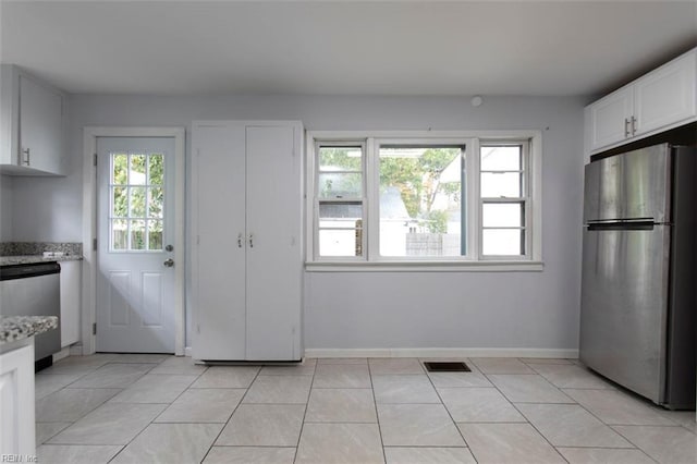 kitchen featuring white cabinetry, light tile patterned floors, light stone counters, and appliances with stainless steel finishes