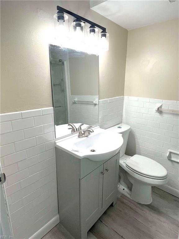 bathroom featuring hardwood / wood-style floors, vanity, toilet, and tile walls