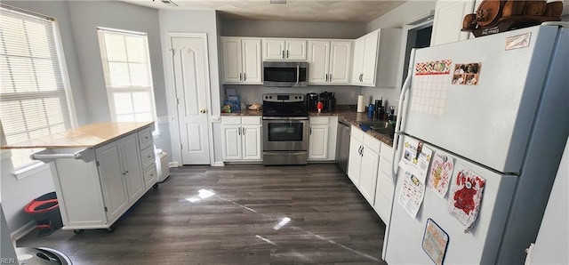 kitchen with white cabinets, a healthy amount of sunlight, dark hardwood / wood-style floors, and appliances with stainless steel finishes