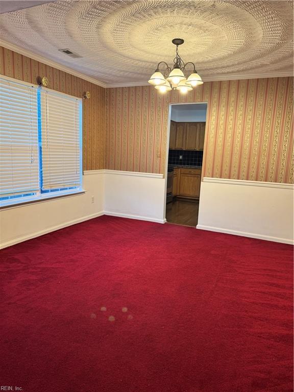 carpeted spare room featuring a notable chandelier