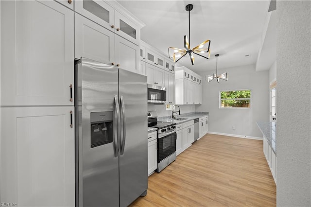 kitchen featuring white cabinets, appliances with stainless steel finishes, an inviting chandelier, and sink