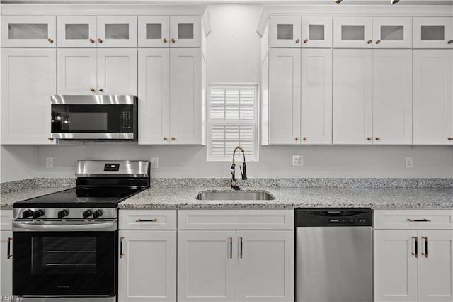 kitchen with light stone countertops, sink, white cabinets, and appliances with stainless steel finishes