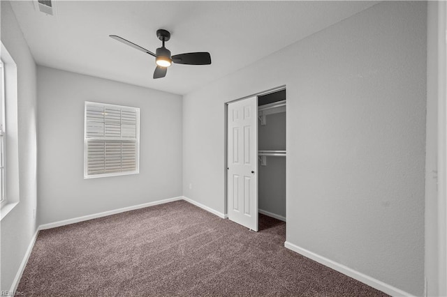 unfurnished bedroom with ceiling fan, a closet, and dark colored carpet