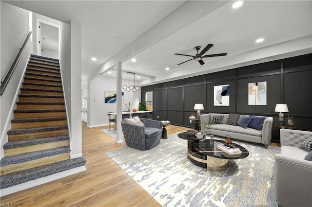 living room featuring ceiling fan with notable chandelier and light hardwood / wood-style floors