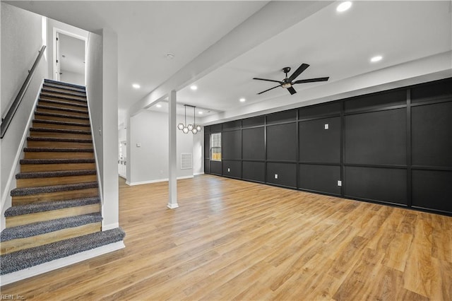 unfurnished living room featuring ceiling fan with notable chandelier and light hardwood / wood-style floors