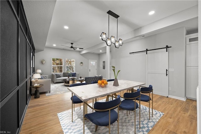 dining room featuring ceiling fan, a barn door, and light hardwood / wood-style floors