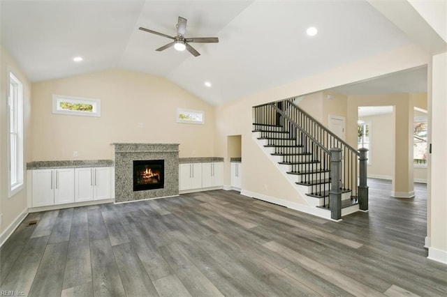 unfurnished living room featuring ceiling fan, a healthy amount of sunlight, and dark hardwood / wood-style flooring