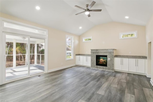 unfurnished living room featuring a wealth of natural light, hardwood / wood-style floors, ceiling fan, and lofted ceiling