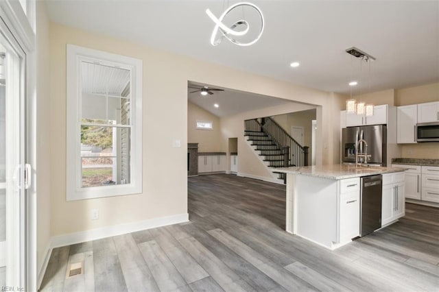 kitchen with ceiling fan, pendant lighting, a kitchen island with sink, white cabinets, and appliances with stainless steel finishes