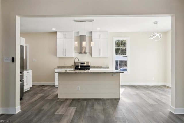 kitchen featuring pendant lighting, white cabinetry, an island with sink, and range hood