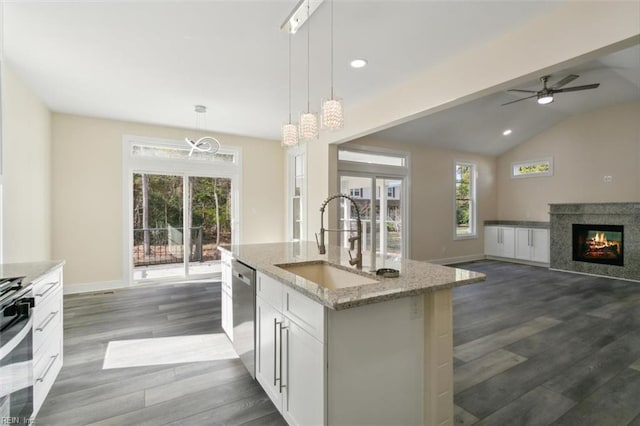 kitchen featuring white cabinets, a kitchen island with sink, sink, dishwasher, and hanging light fixtures