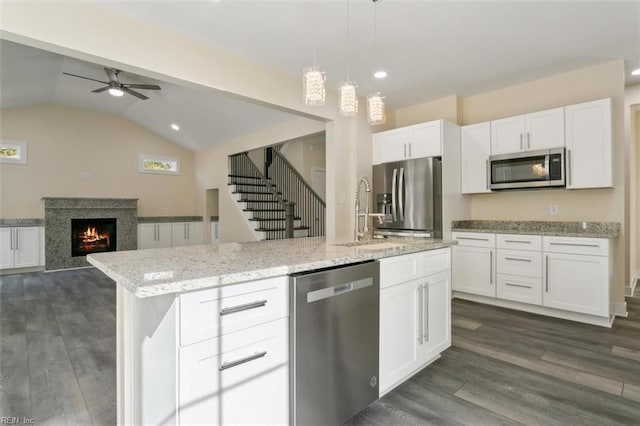 kitchen with white cabinets, dark hardwood / wood-style floors, an island with sink, decorative light fixtures, and stainless steel appliances