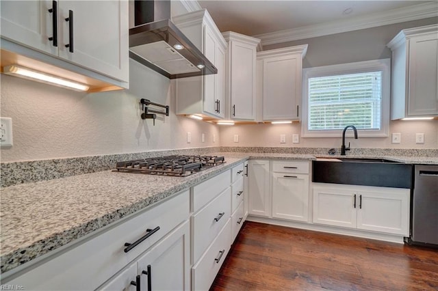 kitchen with white cabinets, wall chimney exhaust hood, light stone countertops, ornamental molding, and stainless steel appliances