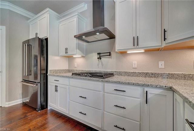 kitchen with white cabinetry, wall chimney exhaust hood, stainless steel appliances, light stone counters, and crown molding