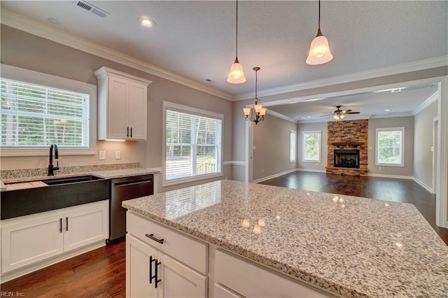 kitchen featuring light stone countertops, white cabinetry, stainless steel dishwasher, and decorative light fixtures