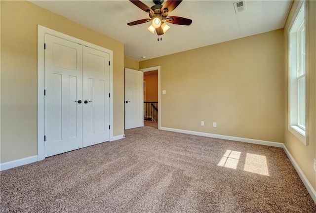 unfurnished bedroom featuring carpet floors, a closet, and ceiling fan