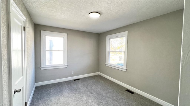 carpeted empty room with a textured ceiling