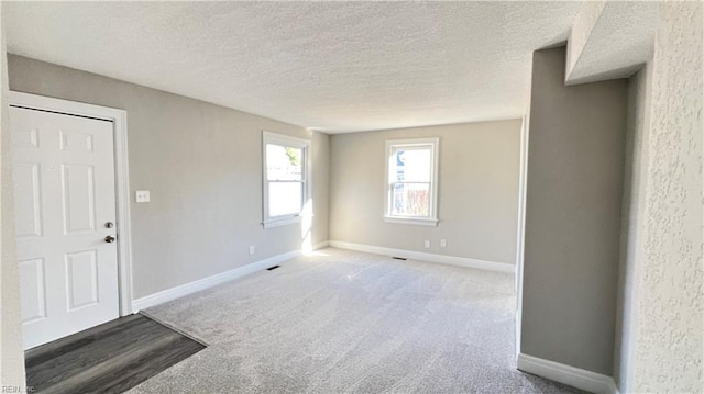 carpeted empty room with a textured ceiling