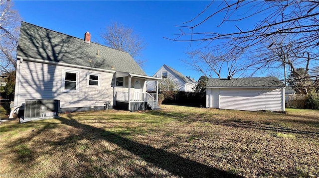 rear view of property with a lawn, an outdoor structure, and central air condition unit