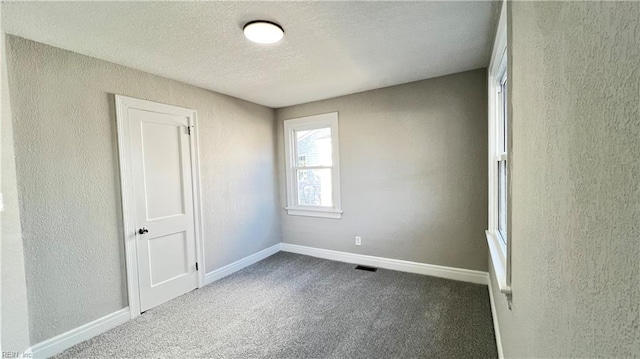 unfurnished room with carpet floors and a textured ceiling