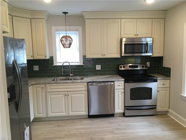 kitchen featuring pendant lighting, sink, light stone countertops, appliances with stainless steel finishes, and tasteful backsplash