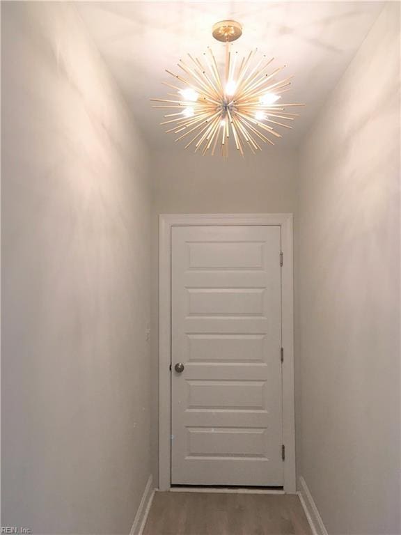 doorway to outside featuring wood-type flooring and an inviting chandelier