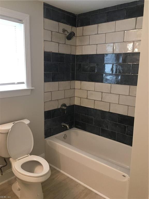 bathroom featuring tiled shower / bath combo, hardwood / wood-style flooring, and toilet