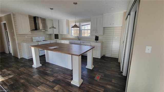 kitchen featuring white range with electric stovetop, white cabinetry, a center island, and wall chimney exhaust hood