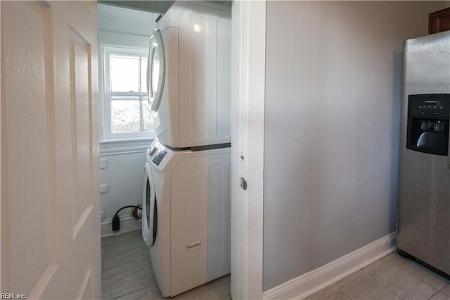 laundry area with light tile patterned floors and stacked washer / drying machine