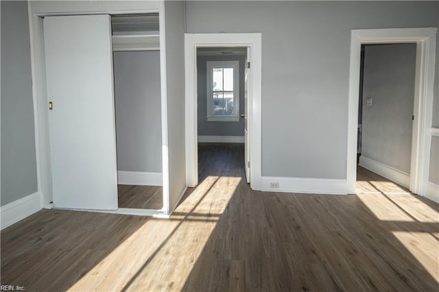 unfurnished bedroom with dark hardwood / wood-style flooring and a closet